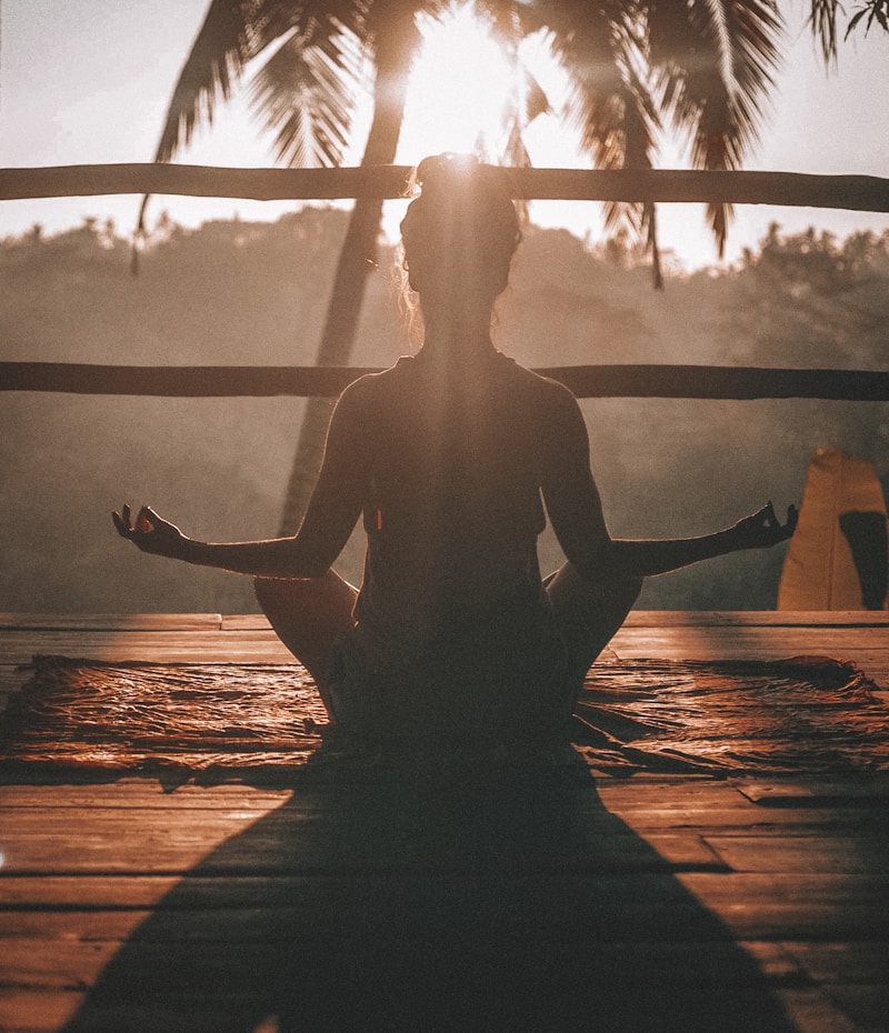 Person meditating in a yoga pose in a peaceful outdoor setting